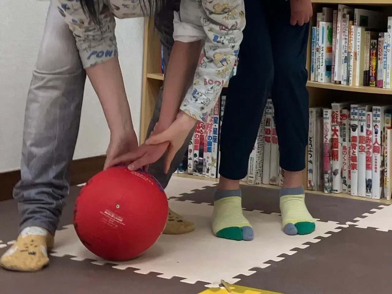 子どもと指導員がボールを転がそうとしているところ